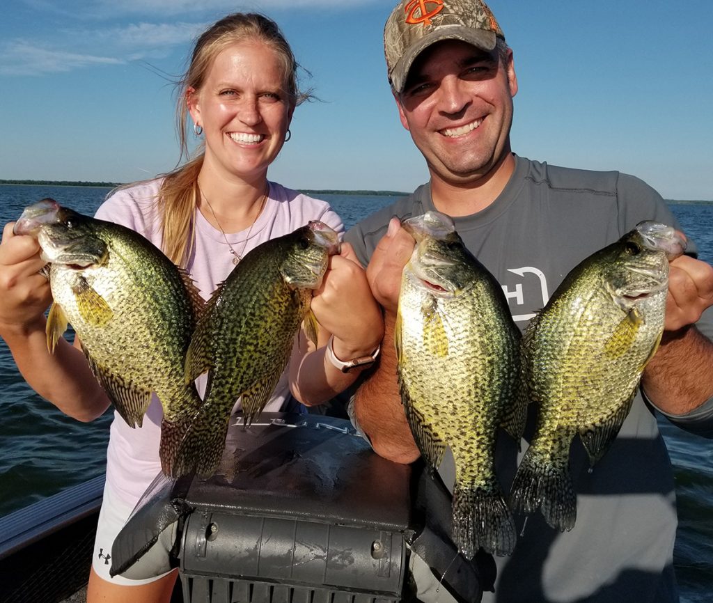 husband and wife pose with the crappies they caught fishing in Minnesota