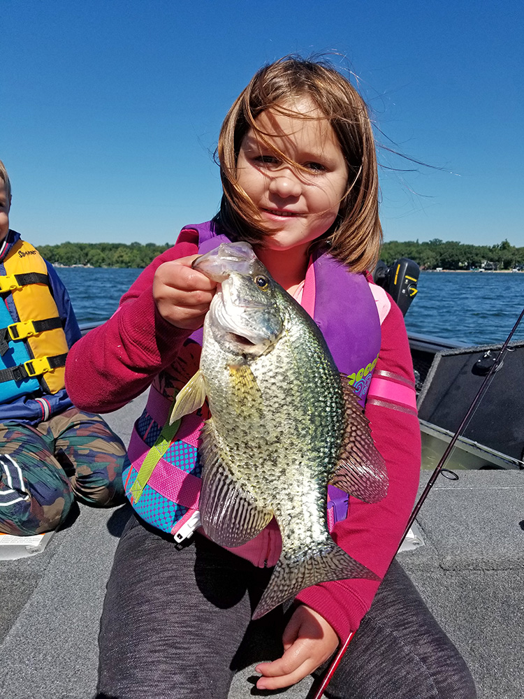 a young girl poses with a large crappie she caught on a lake in Minnesota