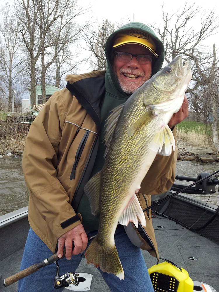 a man is all smiles as he poses with the large walleye he caught with the help of fishing guide Steve Carney