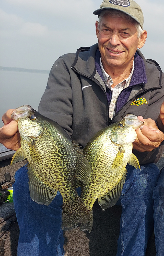 a man holds up two large crappies he caught with guide Steve Carney on a lake In northwestern Minnesota